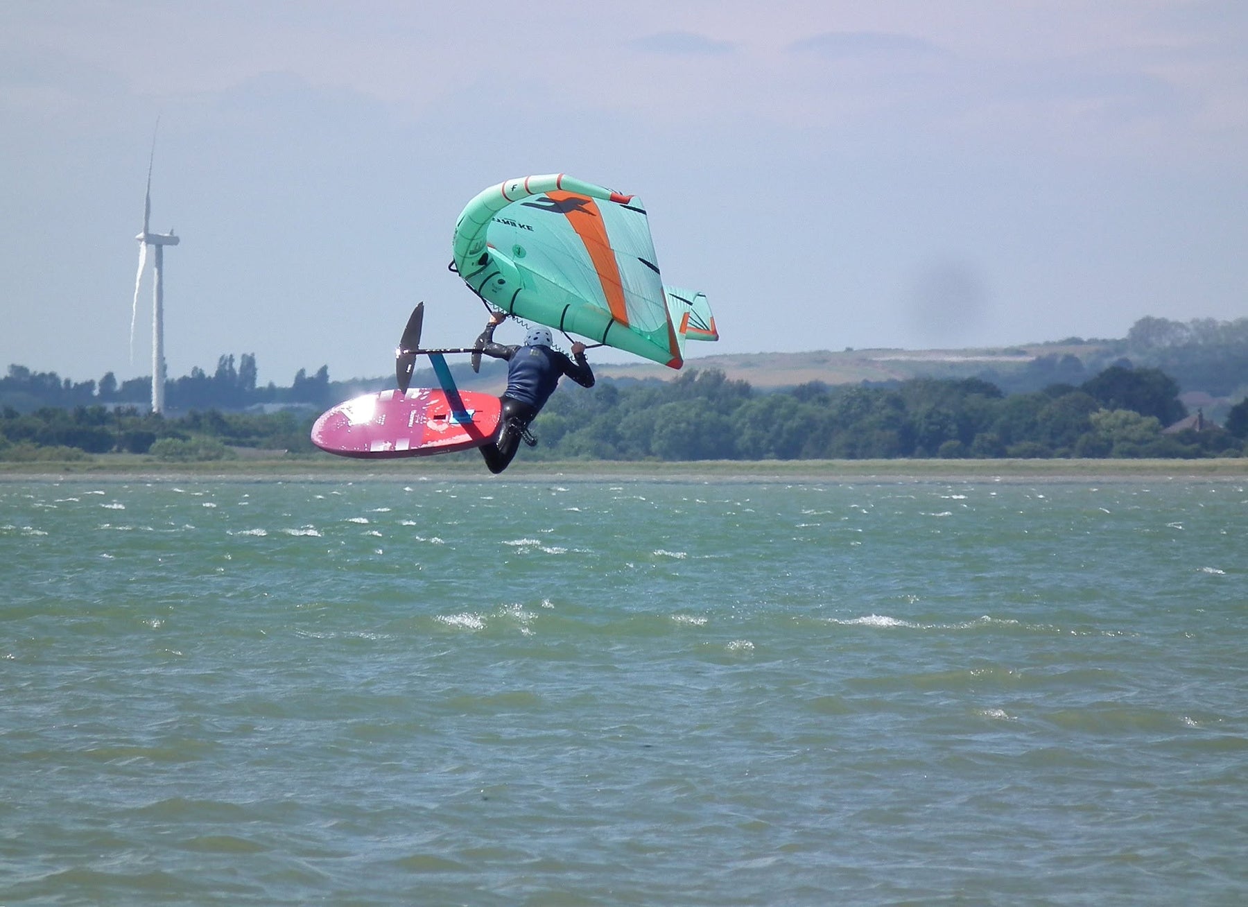 Wing foiler boosting a jump on the Thames Estuary near Whitstable, Kent