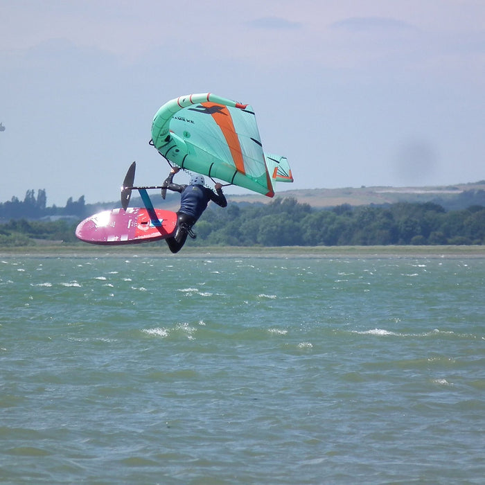 Wing foiler boosting a jump on the Thames Estuary near Whitstable, Kent