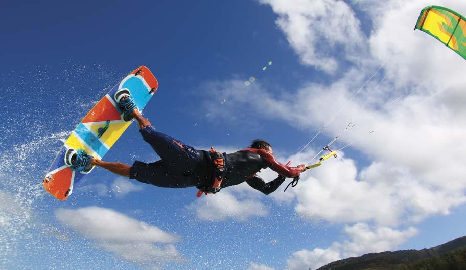 Slingshot Rally kite and Asylum board kitesurfer jumping over water on a sunny day