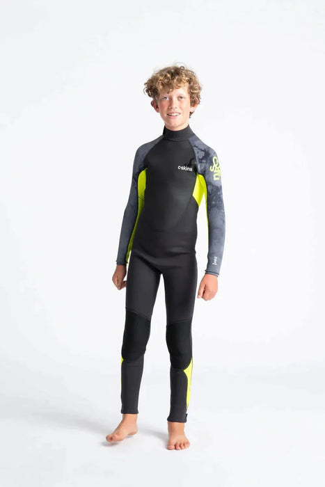 Boy wearing C-Skins Element 3/2 Junior wetsuit in black with yellow and grey accents