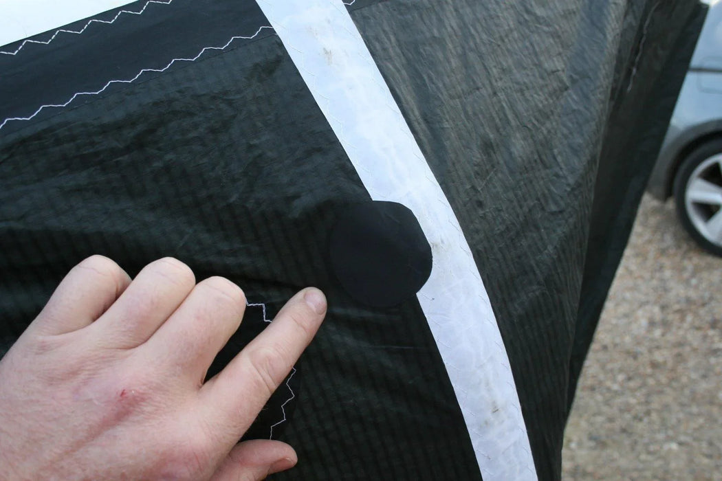 Close-up of a hand inspecting CORE 8M XLite Hydrofoil kite with patch on black fabric