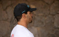 Man wearing black Duotone cap with adjustable strap, side view against stone wall