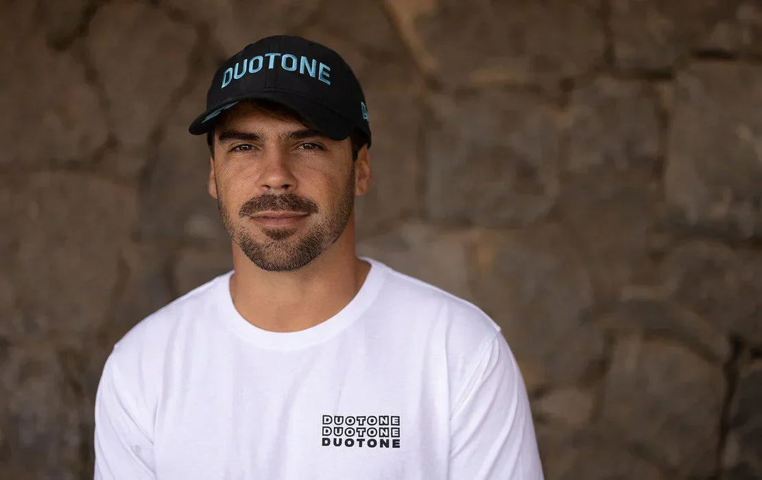 Man wearing black Duotone cap and white Duotone T-shirt, stone wall background