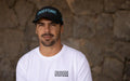 Man wearing black Duotone cap and white Duotone T-shirt, stone wall background