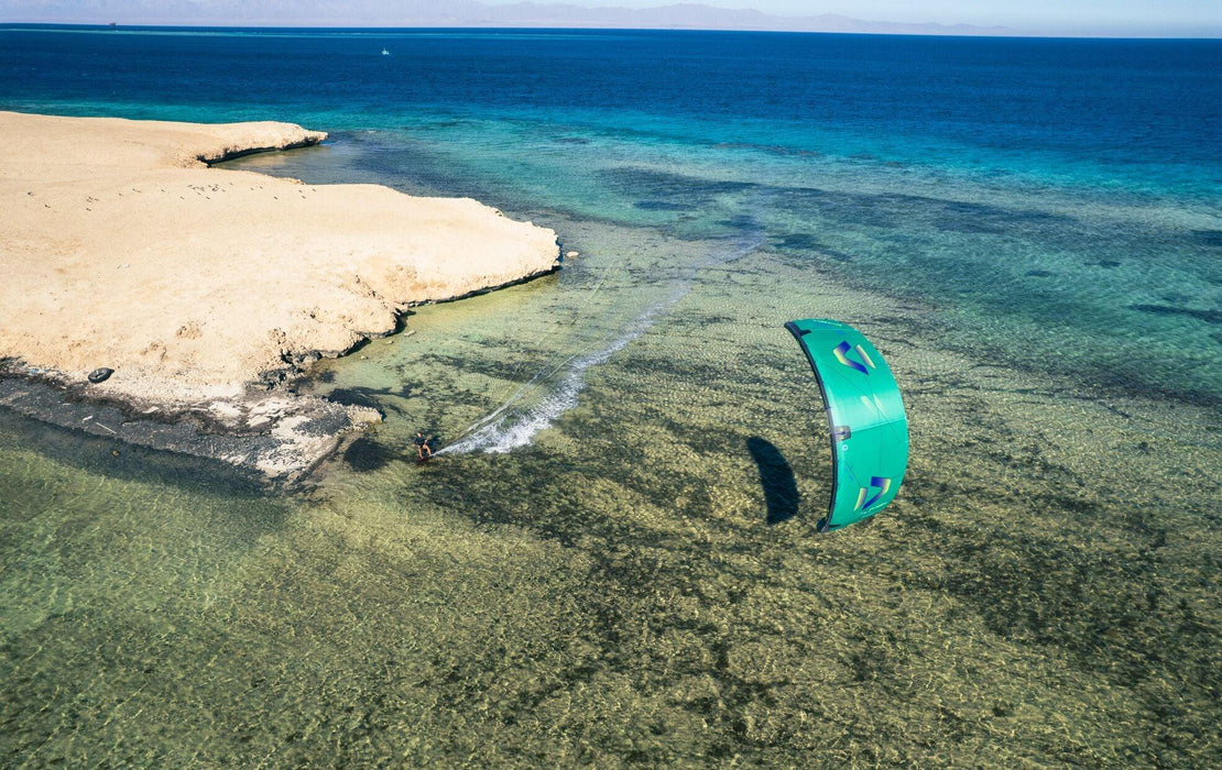 Duotone EVO SLS turquoise kitesurfing kite in action over clear coastal water