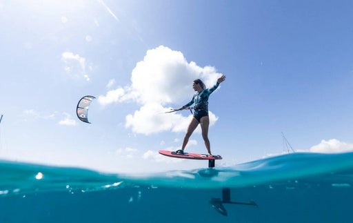Kitesurfer riding duotone hydrofoil board over clear blue water on a sunny day