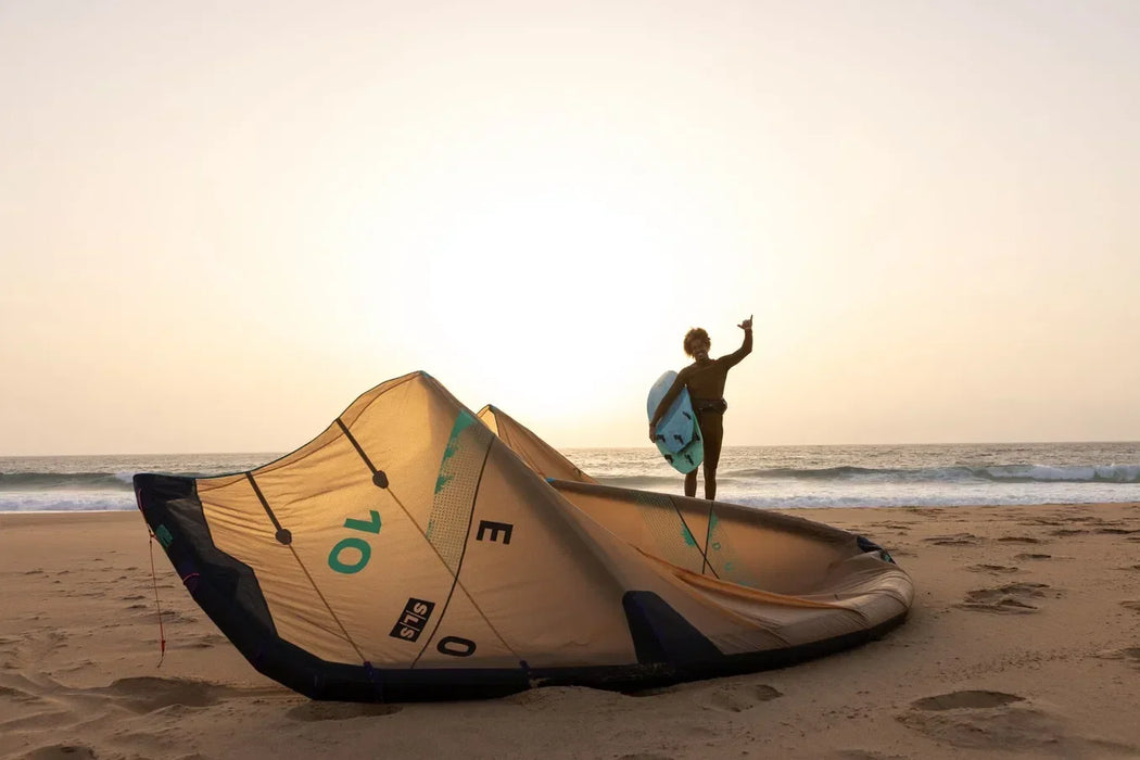 Duotone Neo SLS kitesurfing kite in yellow on sandy beach at sunset, surfer holding board