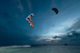 Kitesurfer performing trick with Duotone kite and twintip board over the water at sunset.