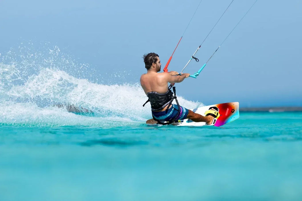 Duotone twintip kiteboard with colourful design in action on clear blue water