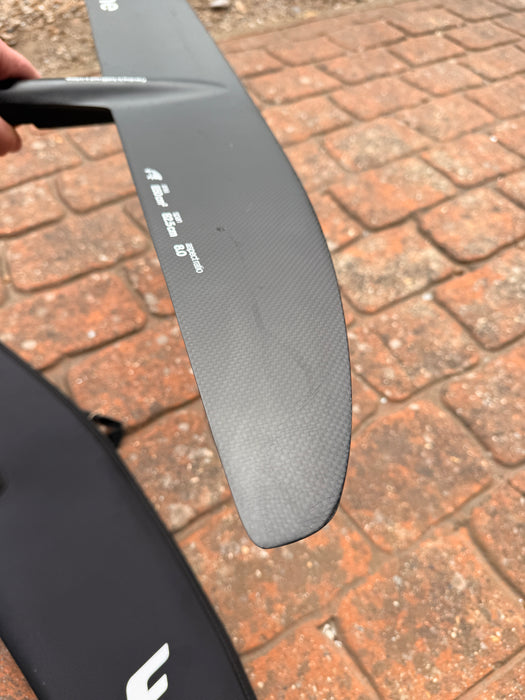 Close-up of wingtip of used F-one Sk8 V2 850 wing foil front wing showing surface scuffs on carbon — disclosed cosmetic marks, no structural damage
