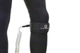 The Foil Board Company coiled wingboard knee leash in black, worn on wetsuit-clad leg.