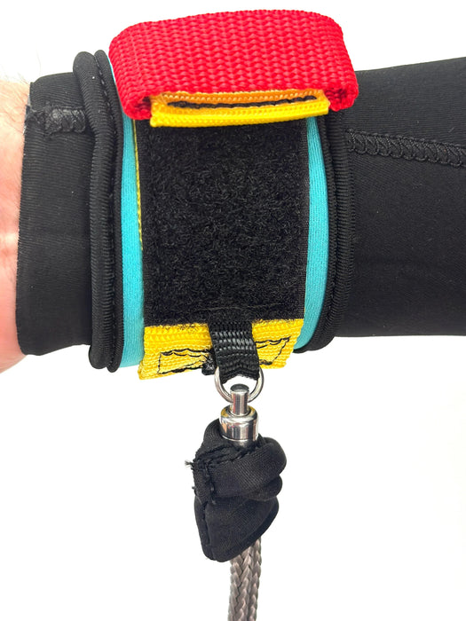 Close-up of FBC wing foil wrist leash with red strap, black Velcro, and yellow trim on wetsuit sleeve