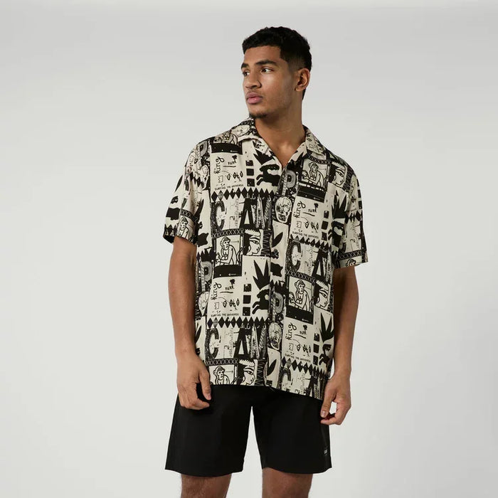 Beige short sleeve surf shirt with black abstract print, worn with black board shorts