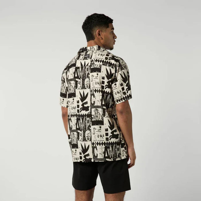Man wearing sand color graphic surf shirt and black shorts, back view, watersports clothing