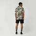 Man wearing a Mystic black and sand print surf shirt with black shorts and socks