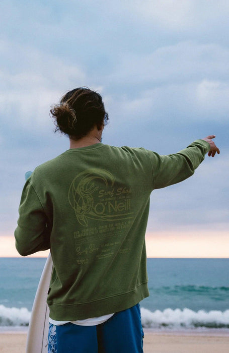 O'Neill green crew sweatshirt for surfers, back view, beach setting, surfboard in hand