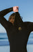 O'Neill black chest zip wetsuit with yellow logo, worn by person at the beach
