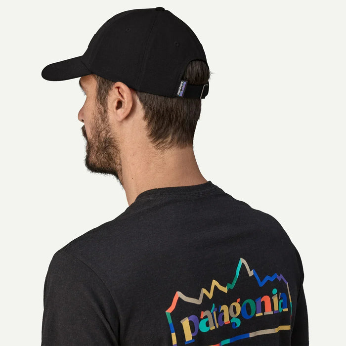 Patagonia P-6 Label Trad Cap in black, adjustable strap, worn by man with Patagonia logo shirt