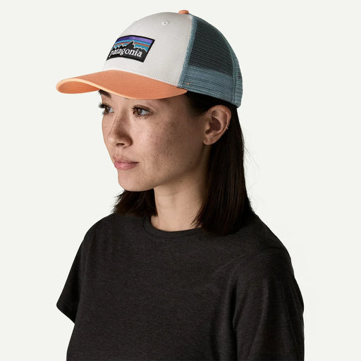 Patagonia P-6 Logo Lopro Trucker Hat in white, peach, and blue mesh, worn by woman
