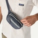 Patagonia Terravia Mini Hip Pack 1L in coal grey, worn crossbody, shown unzipped