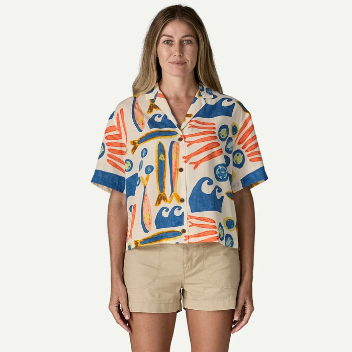 Woman wearing Patagonia short sleeve shirt with colourful sardines and wave print, natural colour.
