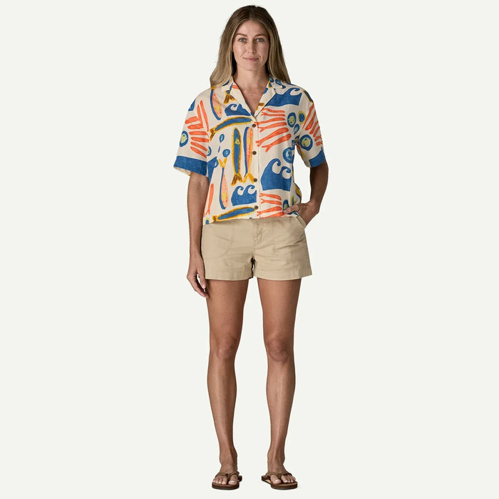 Woman wearing Patagonia short sleeve shirt with colourful sardine and wave print, beige shorts