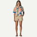 Woman wearing Patagonia short sleeve shirt with colourful sardine and wave print, beige shorts