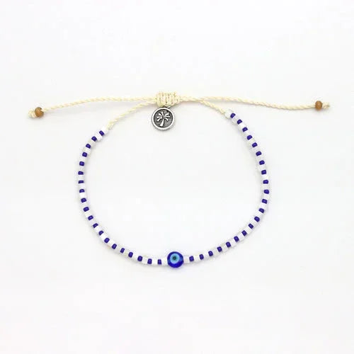 White and blue evil eye anklet with adjustable cord and small round charm, laid flat