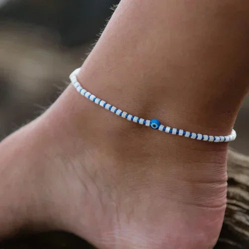 blue and white beaded anklet with eye charm on ankle, ideal surf jewelry for beachwear