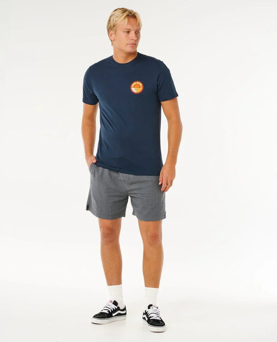 Rip Curl navy stacked tee with logo chest print, worn by man in casual beachwear