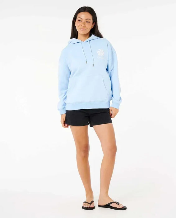Rip Curl Shore Break Heritage light blue hoodie with white logo, worn by woman in casual beachwear