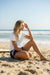 Woman wearing dark navy Rip Curl boardshorts with rainbow stripe sitting on beach