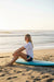 Woman wearing Rip Curl Surf Side 5 dark navy boardshorts sitting on surfboard at beach