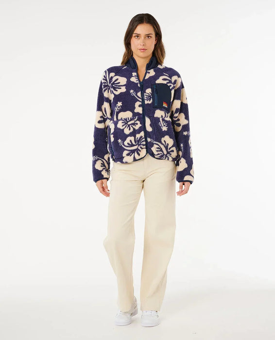 Rip Curl navy polar fleece jacket with cream floral print, worn by woman standing