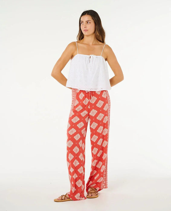 Rip Curl Ventura wide leg red pants with white floral pattern, modeled by woman in sandals.