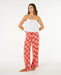 Rip Curl Ventura wide leg red pants with white floral pattern, modeled by woman in sandals.