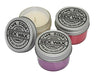 Mr. Zog's Sex Wax scented candles in tins, displayed in white, pink, and purple.