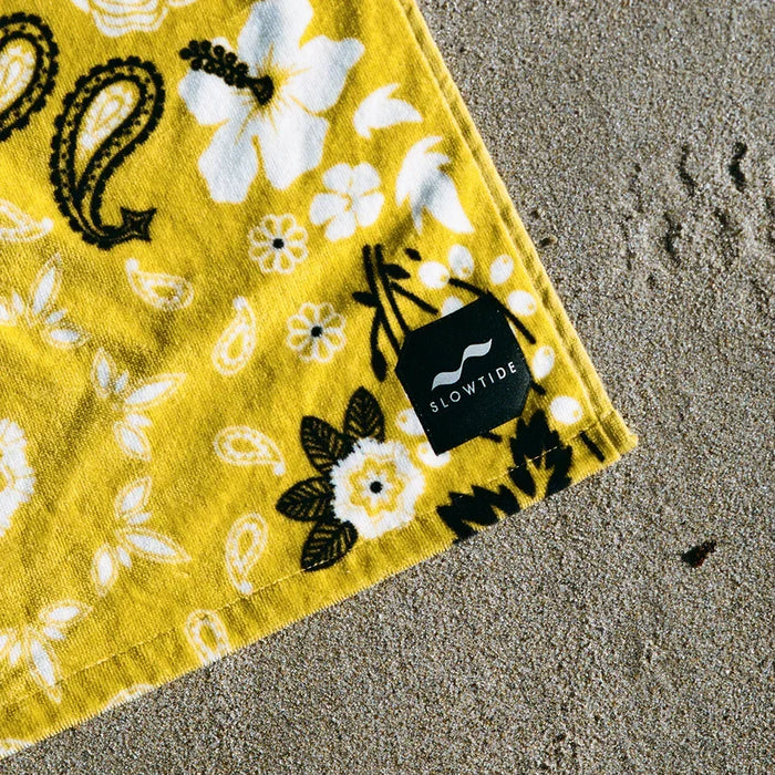 Slowtide yellow floral beach towel with white and black pattern on sand