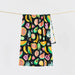 Slowtide beach towel with colorful tropical fruit print on black background, hanging on rope