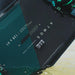 Atmos kiteboard with black and teal striped deck, Woo sensor mounted on top, in water.